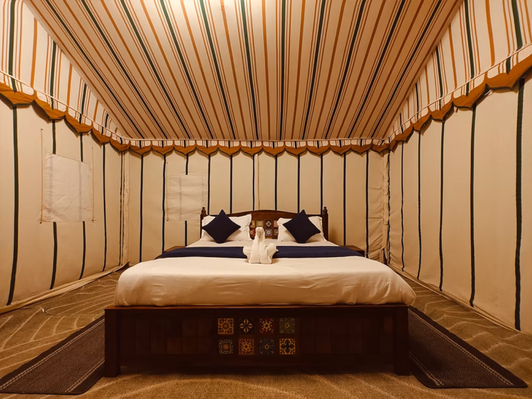 Wooden king bed inside the Deluxe Swiss Tent in Jaisalmer