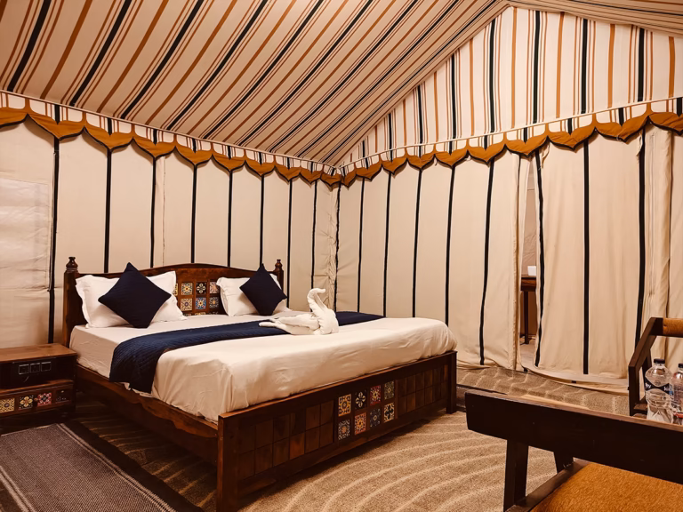Deluxe Swiss Tent bedroom with wooden king bed and traditional decor