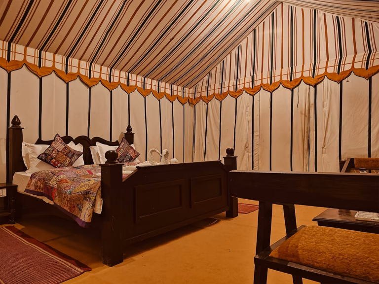 Super Deluxe Swiss Tent bedroom with wooden king bed and seating area
